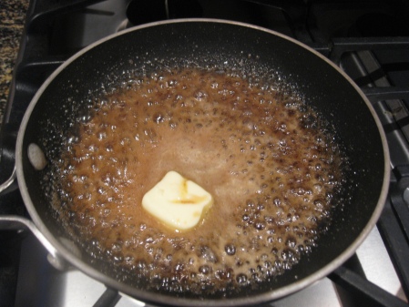 Adding the butter to the reduced rum and brown sugar